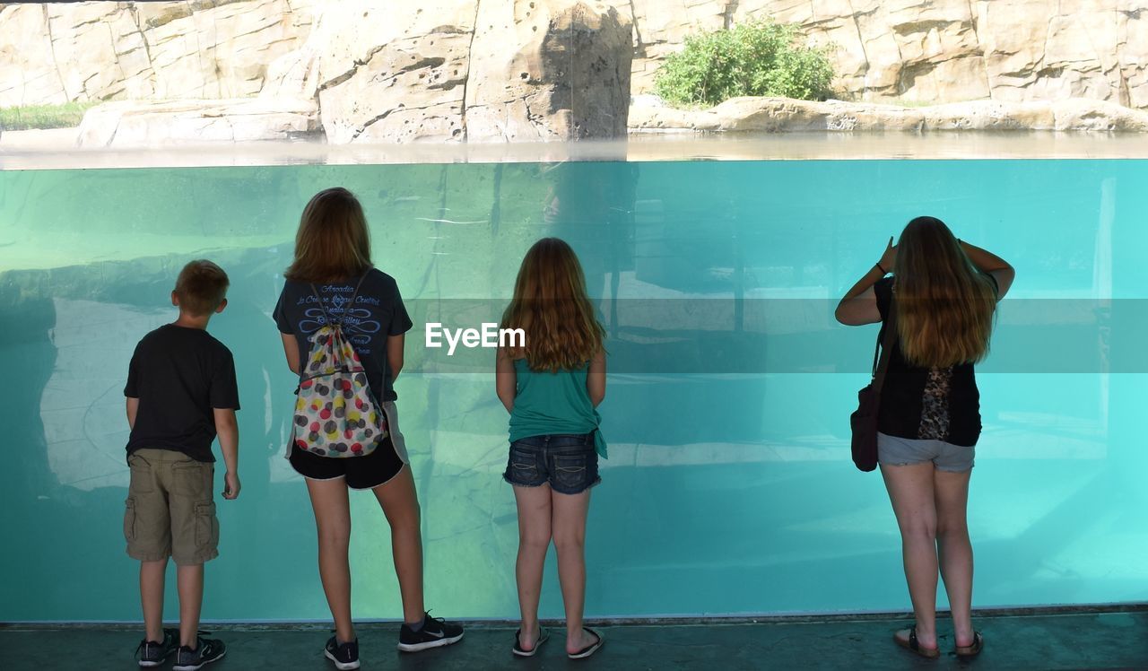 REAR VIEW OF WOMAN STANDING IN SWIMMING POOL