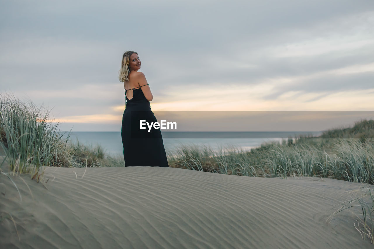 Woman standing on beach against sky