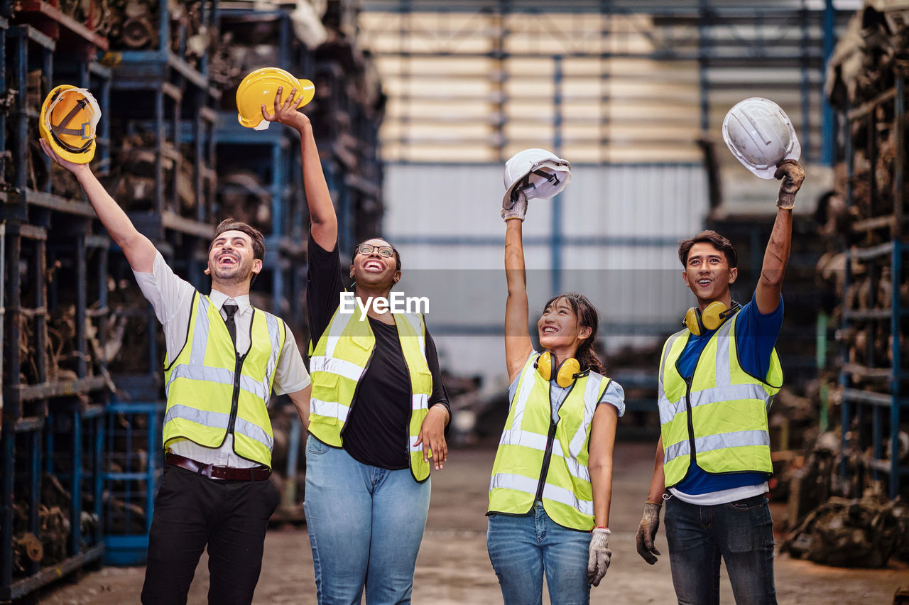 Confident poses team engineers raised their hands in the air as they held their helmets safety