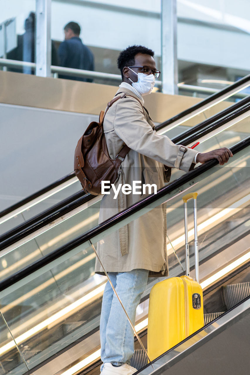 Man wearing mask standing on escalator