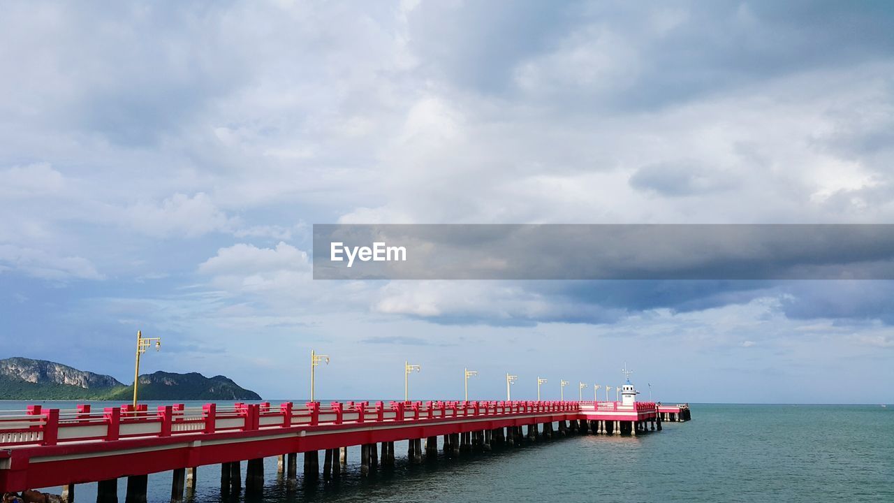 Bridge over sea against cloudy sky