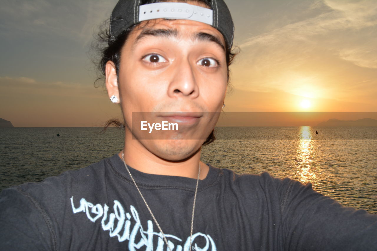 PORTRAIT OF MAN AT BEACH AGAINST SKY