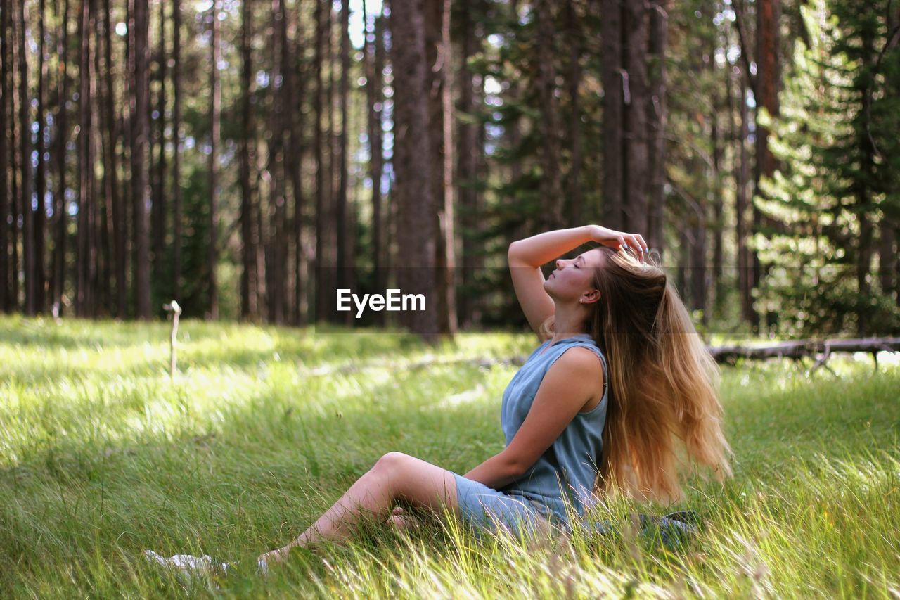 Side view of woman with long hair relaxing on grassy field