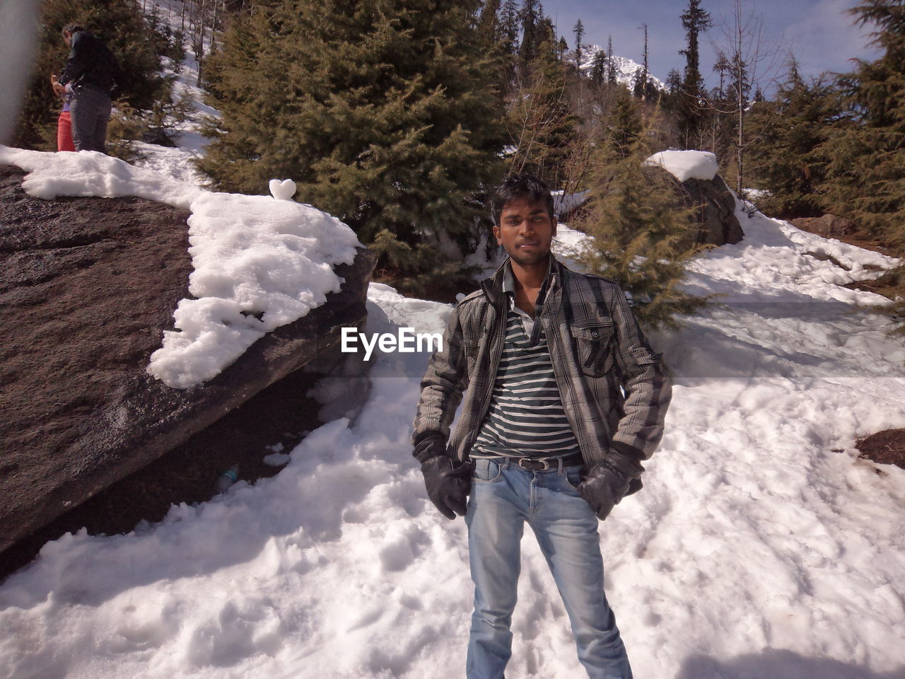 Portrait of young man standing on snowcapped mountain
