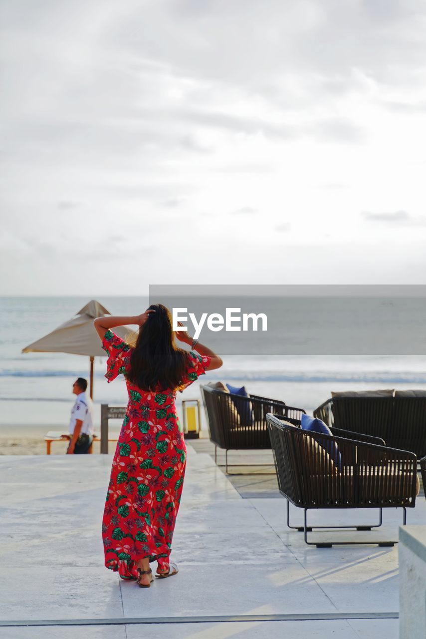 Rear view of woman on beach against sky