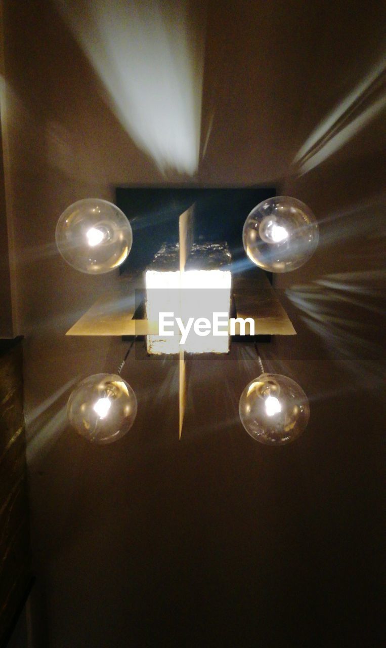 LOW ANGLE VIEW OF ILLUMINATED LIGHT BULB HANGING ON CEILING