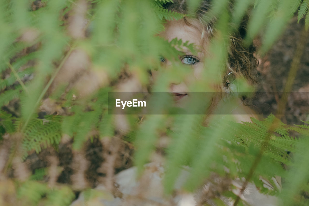 Close-up portrait of young woman seen through plant