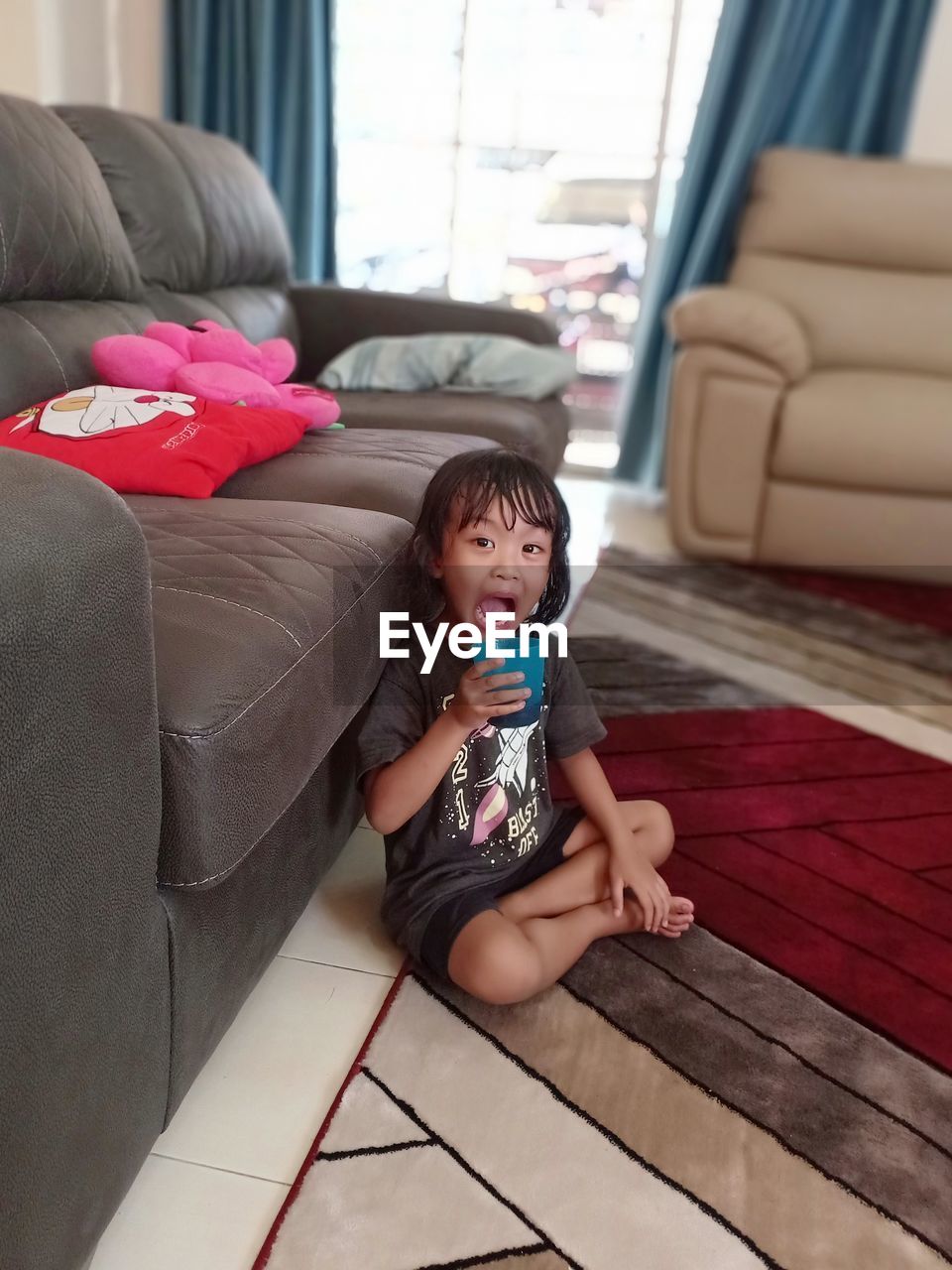 PORTRAIT OF CUTE BABY GIRL SITTING ON SOFA AT HOME