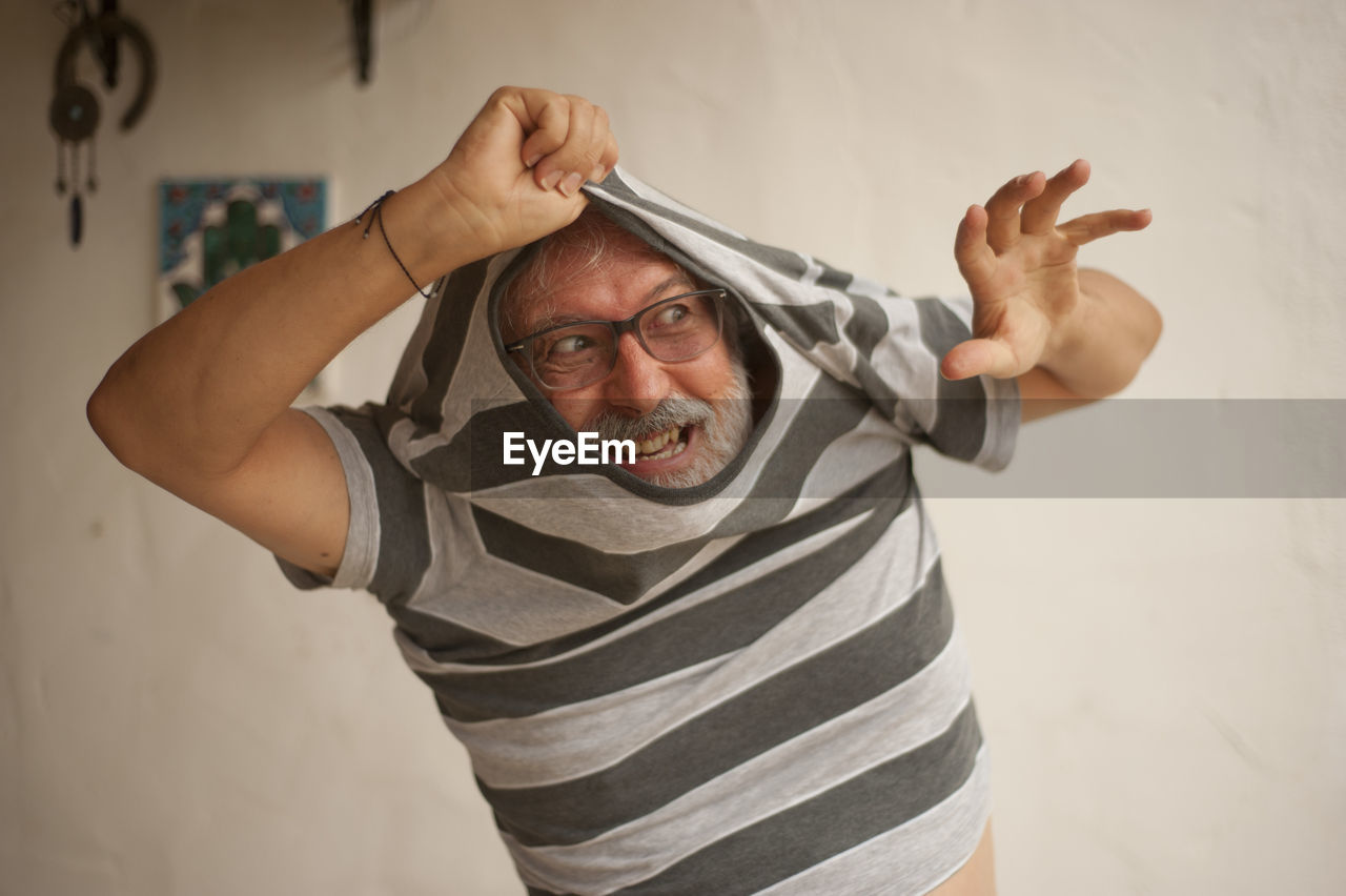 Senior man removing striped t-shirt at home