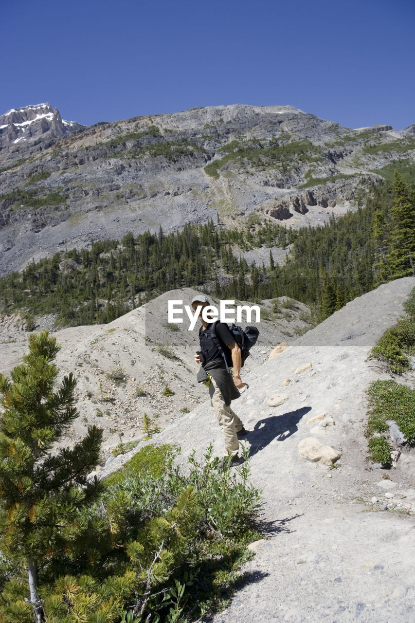 Man standing on rocky mountain against clear blue sky