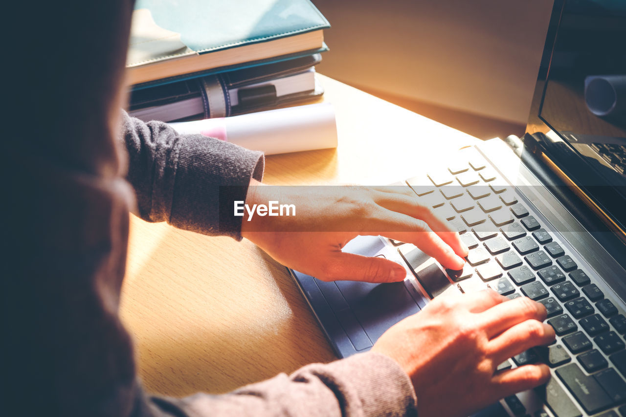 Cropped hands of person using laptop at desk