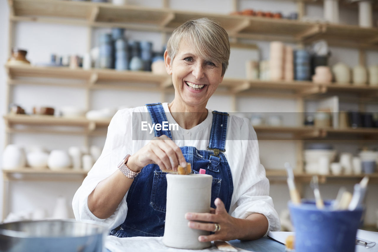 Portrait of smiling mature woman learning pottery in art studio
