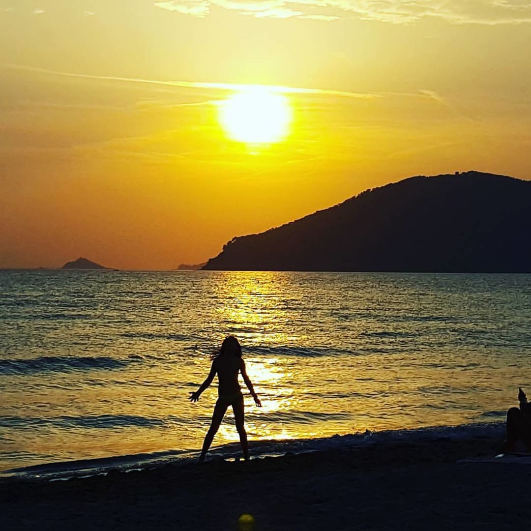 SILHOUETTE WOMAN STANDING AT BEACH DURING SUNSET