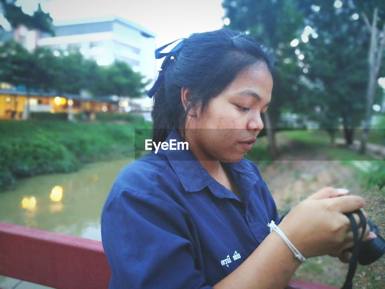 CLOSE-UP OF YOUNG WOMAN WITH TREES IN BACKGROUND