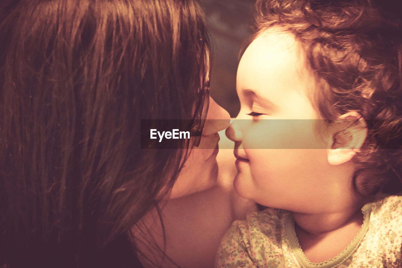 Loving mother and daughter touching noses while showing affection to each other.