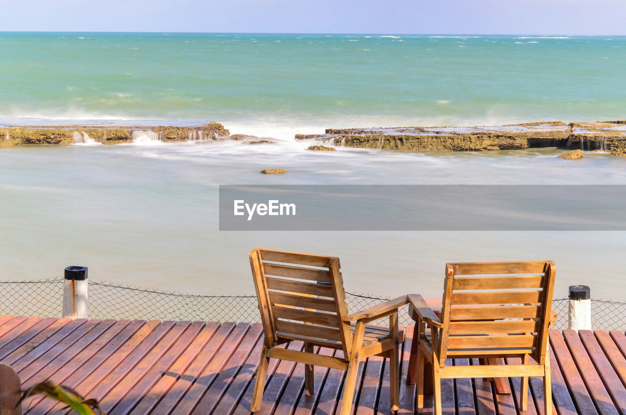 CHAIRS AND TABLE BY SEA AGAINST SKY