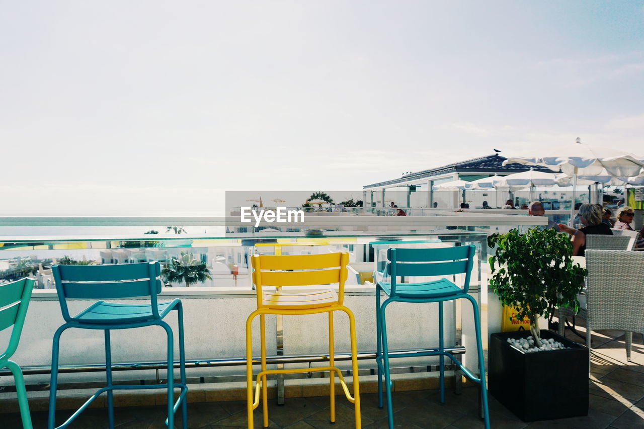 Empty chairs and tables against clear sky