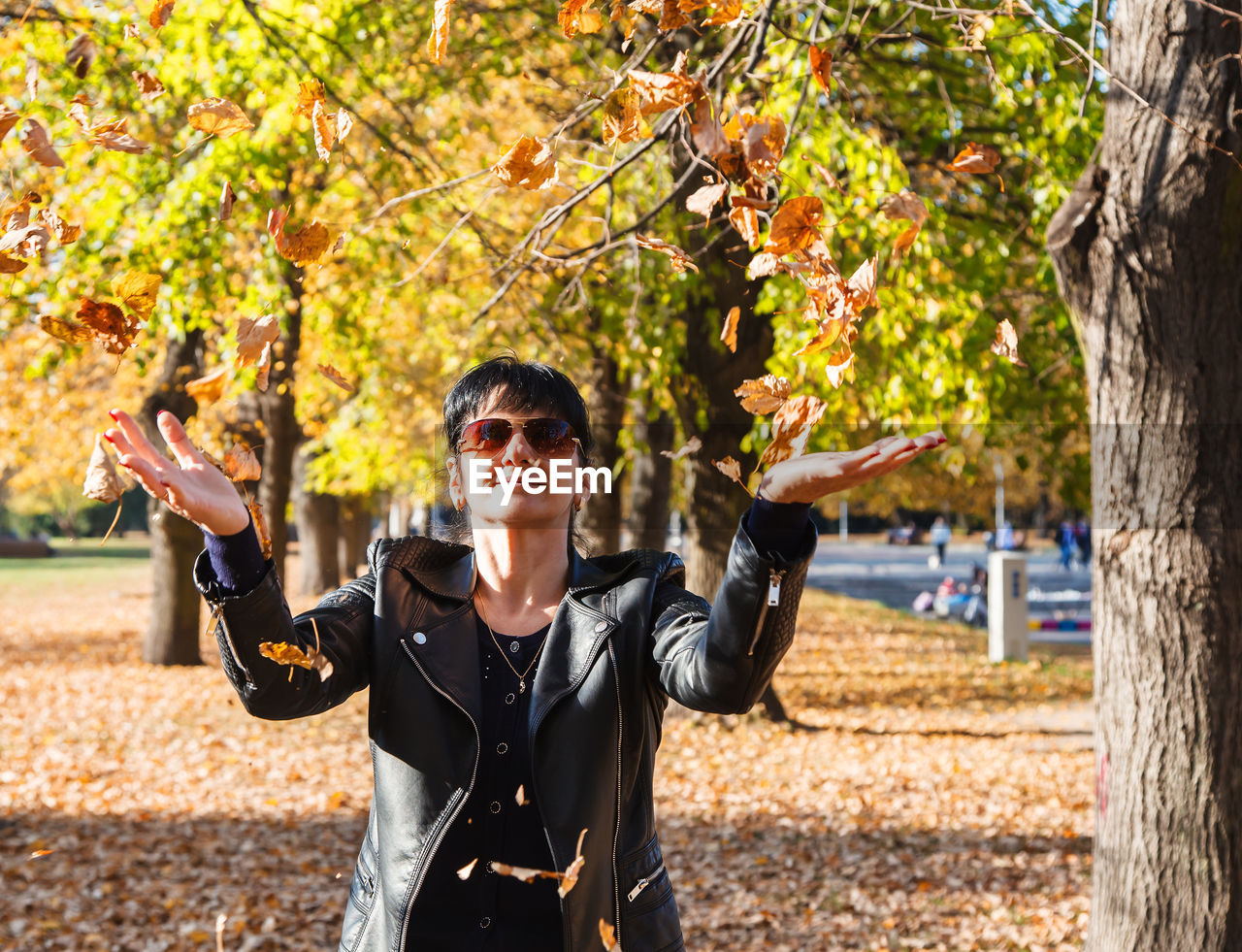 Woman with sunglasses standing on autumn leaves
