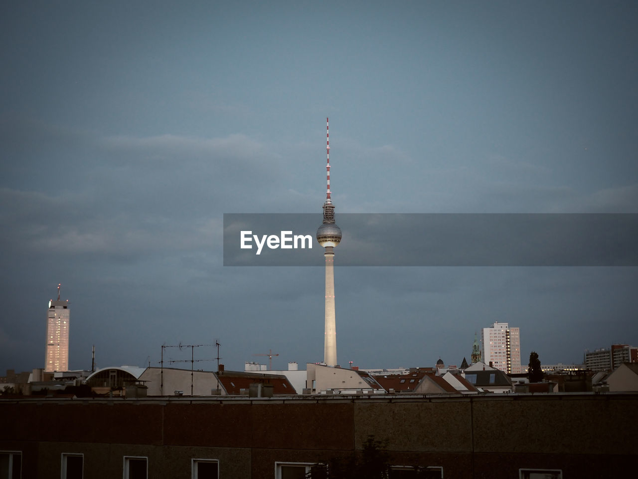 View of communications tower in city against sky