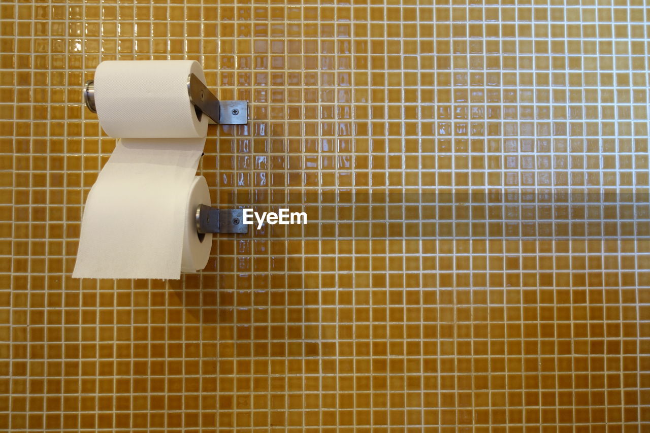 Close-up of toilet papers on tiled wall