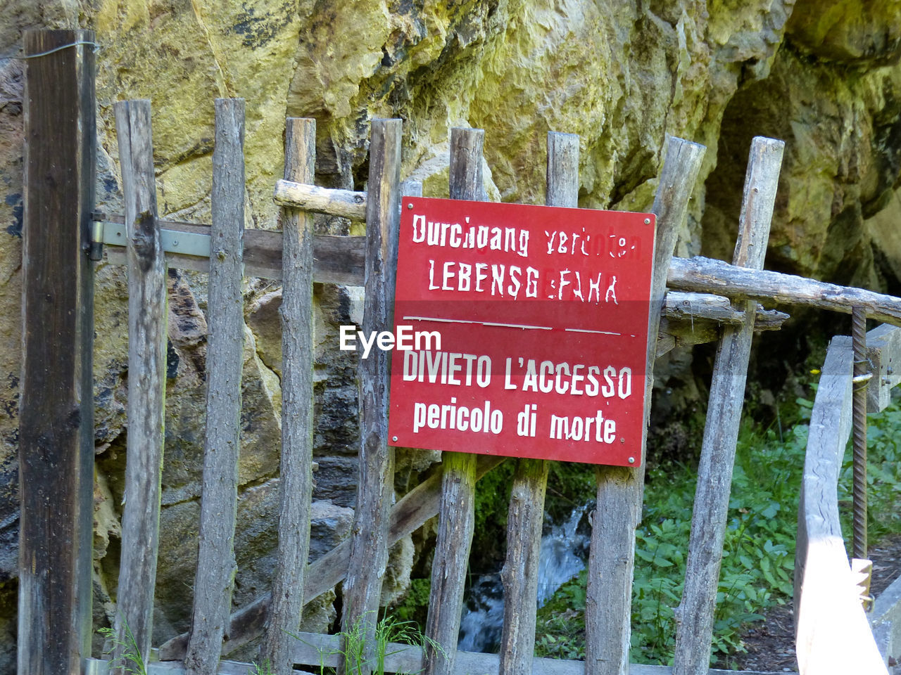 Warning sign on wooden fence