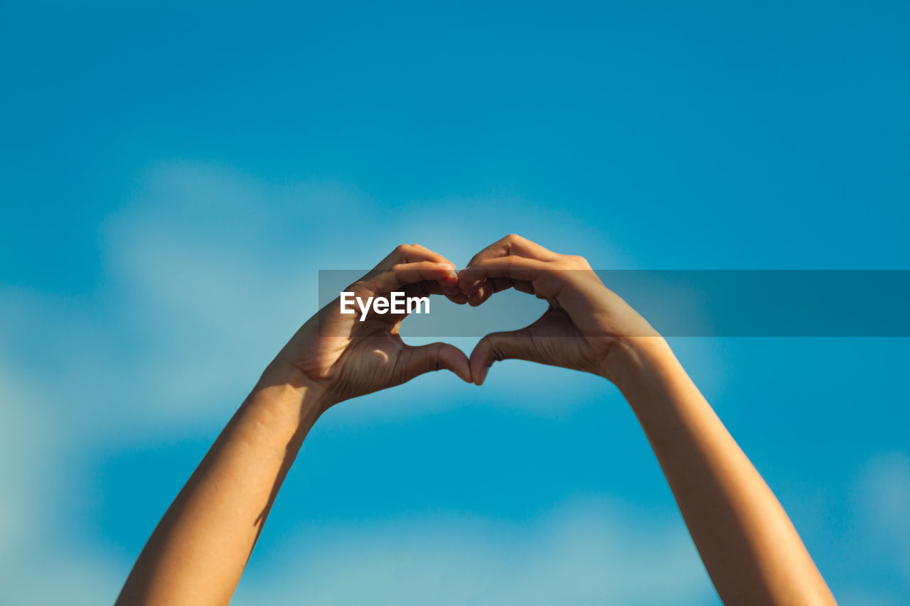 Cropped image of woman gesturing against sky