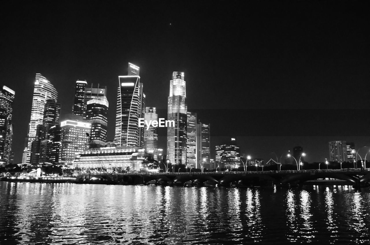 Illuminated city skyline by river at night