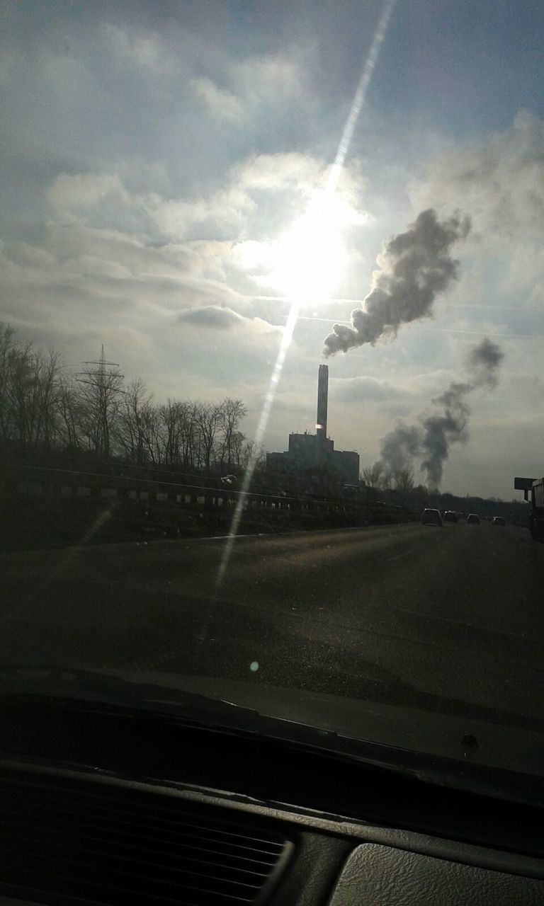 SUN SHINING THROUGH CLOUDS OVER ROAD