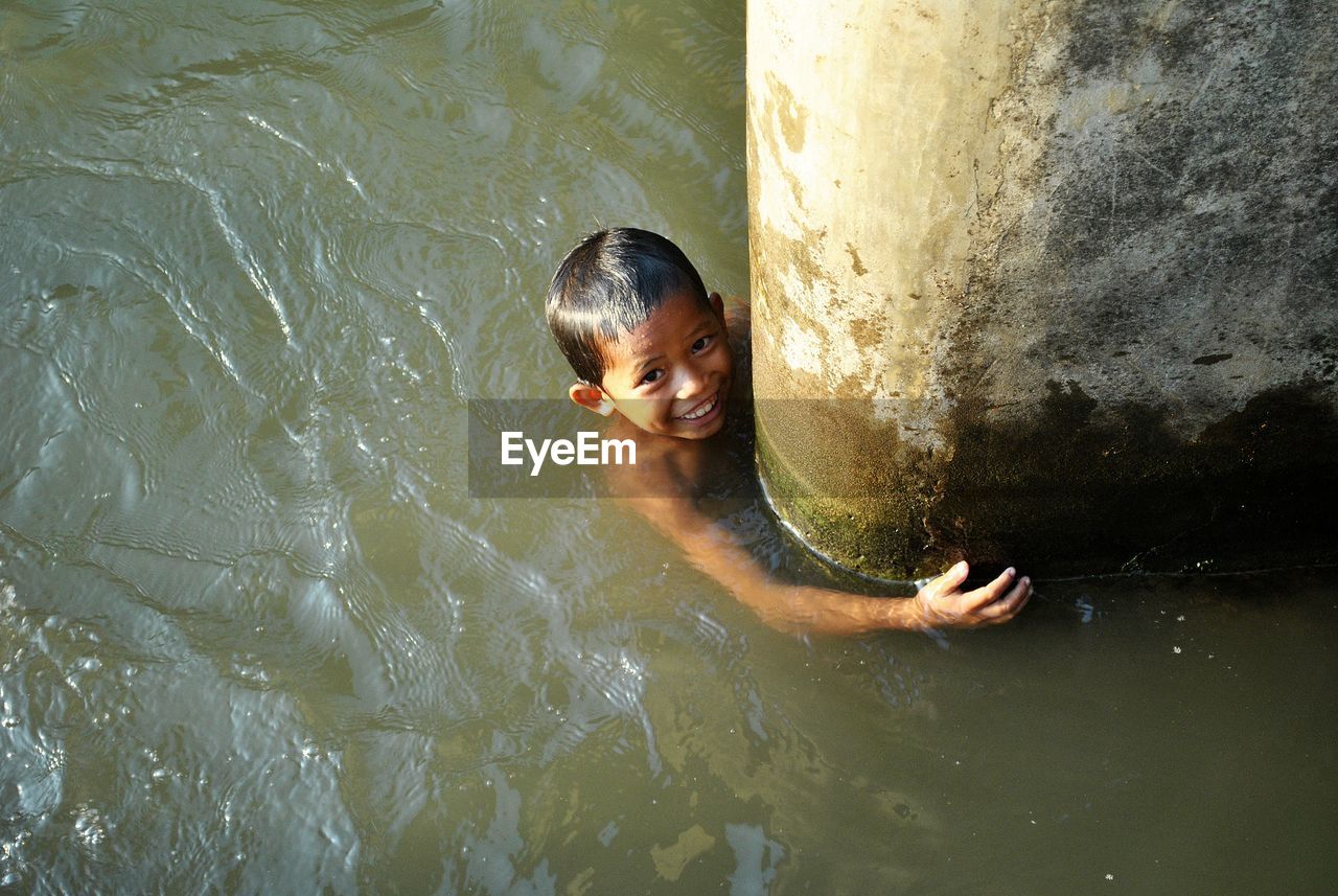 High angle portrait of shirtless boy swimming in lake