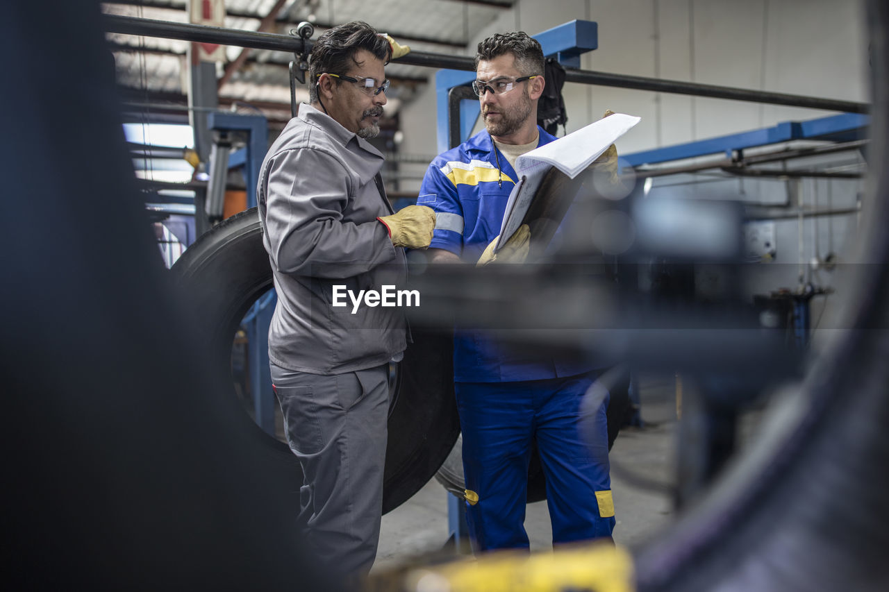 Two tire repairmen with clipboard talking