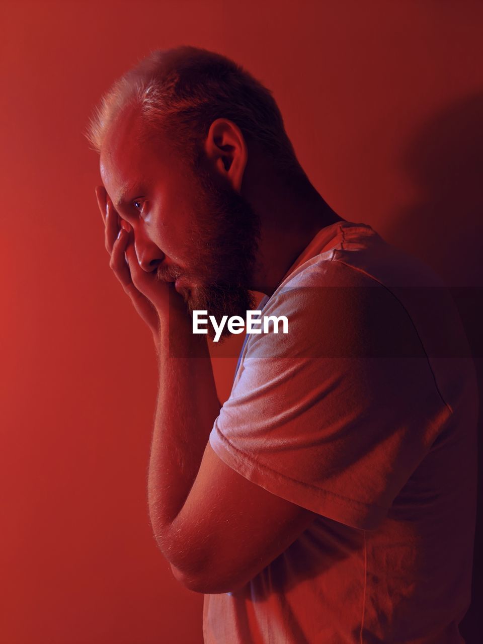 Side view of man against wall in red room