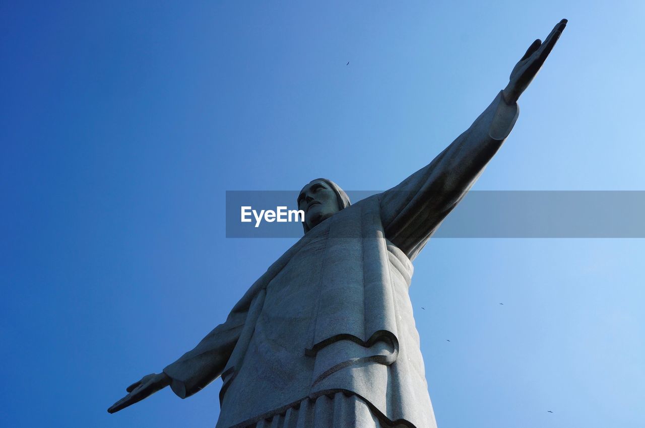 Low angle view of jesus statue against clear blue sky