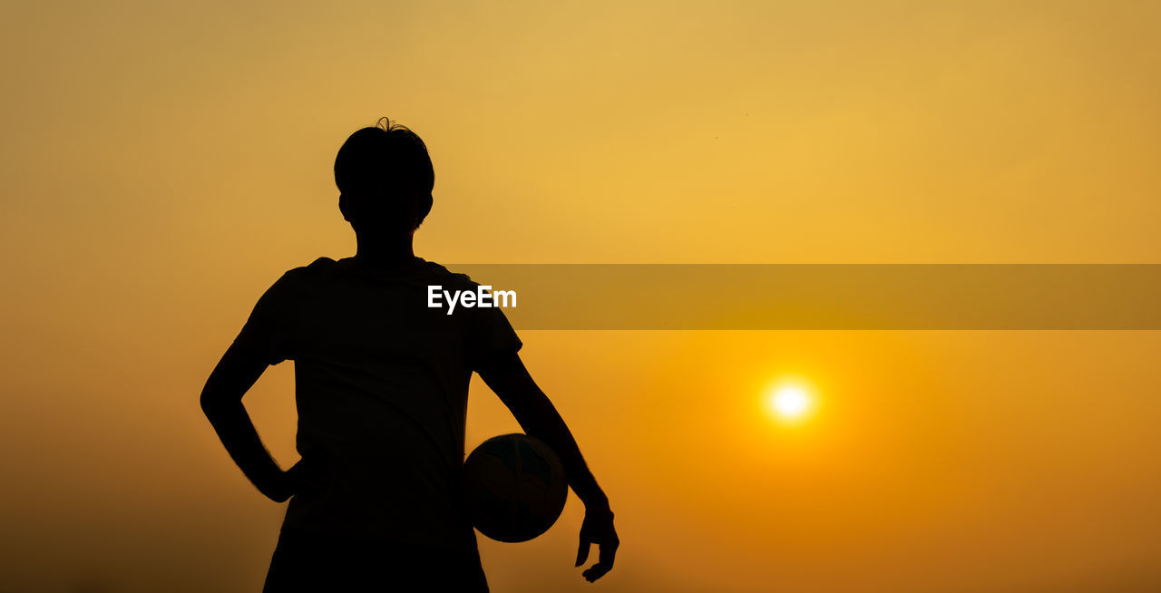 Silhouette man standing against orange sky