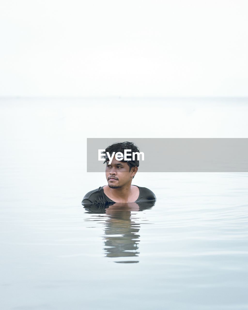 Portrait of young man swimming in sea against clear sky