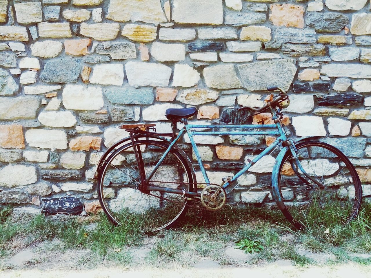 Blue bike leaning against stone wall