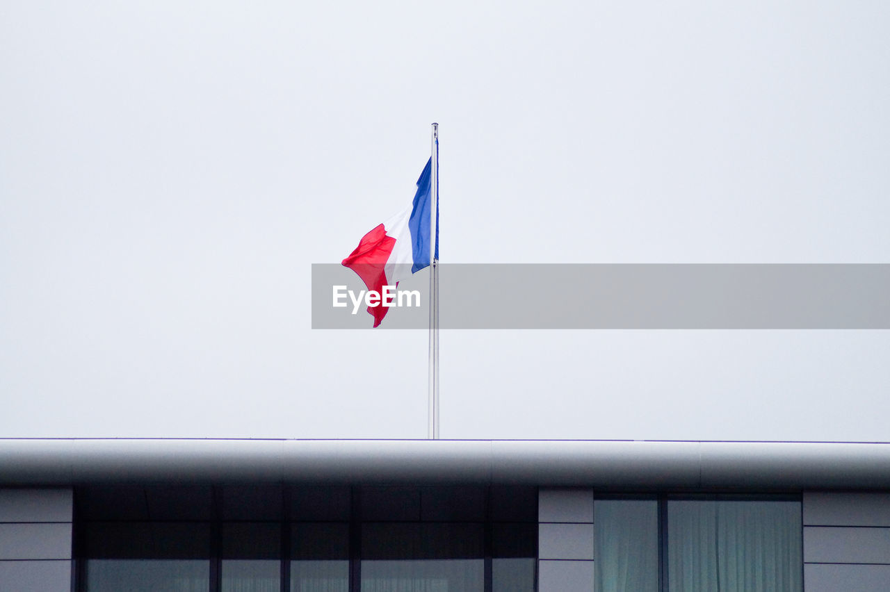 Low angle view of french flag waving on building against clear sky