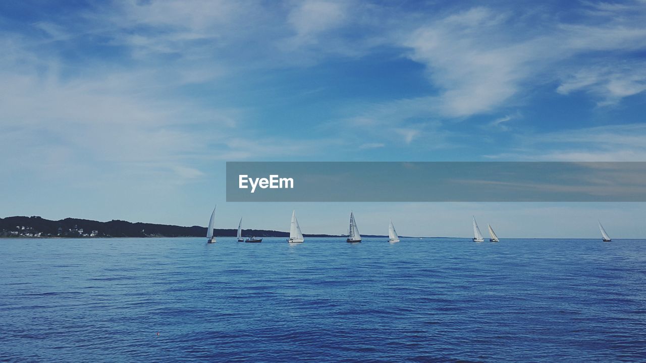 Sailboats sailing in sea against sky