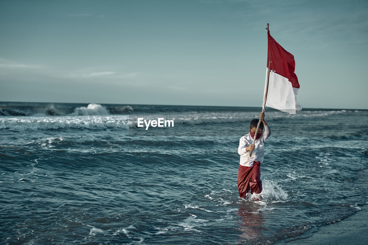 Woman with umbrella on sea against sky