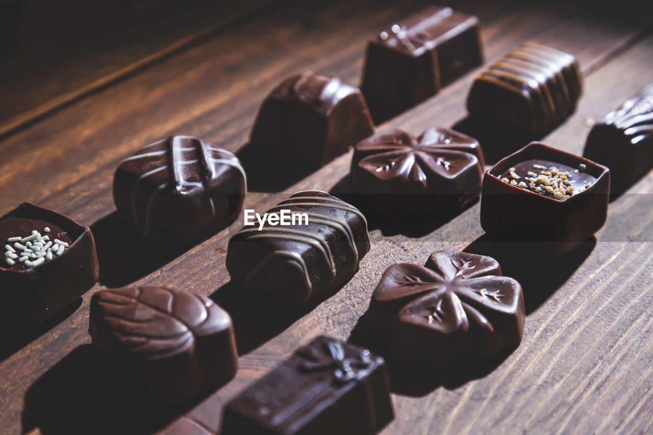 Pralines on wooden base, deep shadows, close up. sweet and chocolate concept.