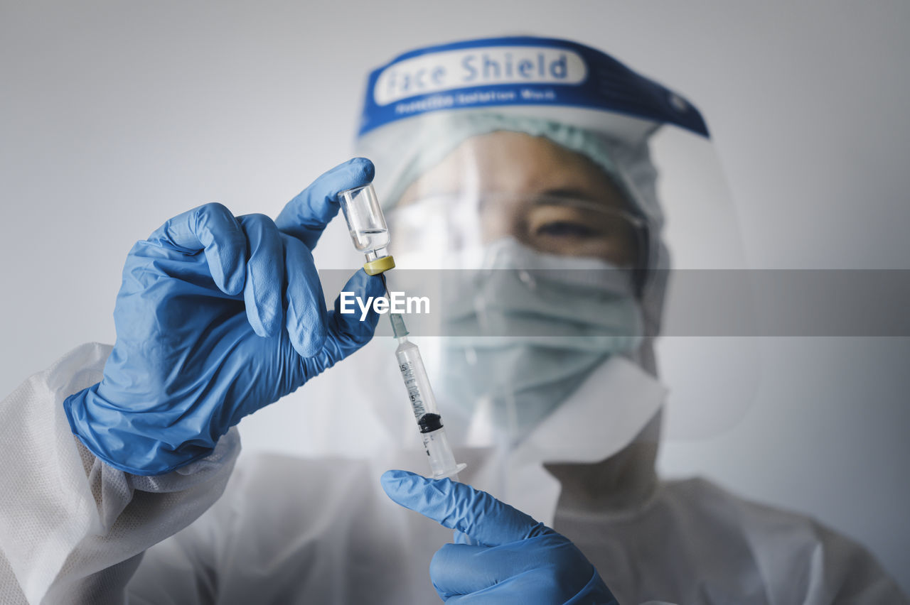 Close-up of doctor wearing surgical mask against white background