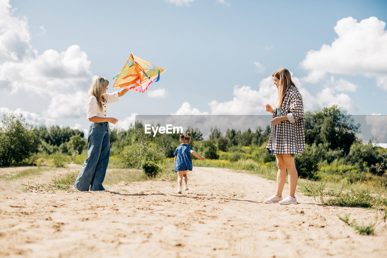 A mother flies a kite with her daughters during a family vacation in the country