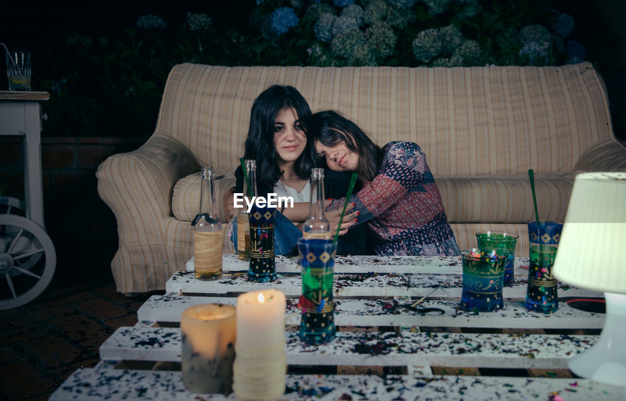 Young woman embracing friend during party in backyard at night