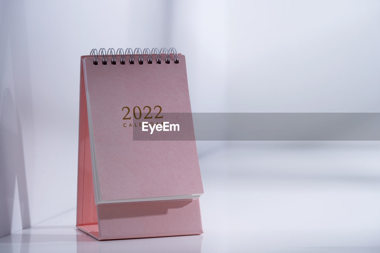 Pink desk 2022 calendar on table top near window