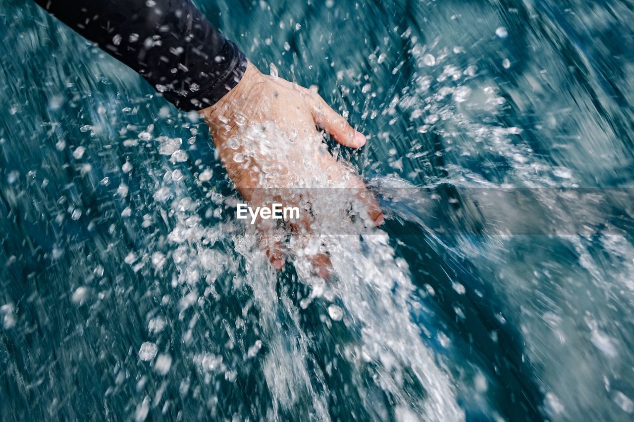 Cropped hand of person splashing water in sea
