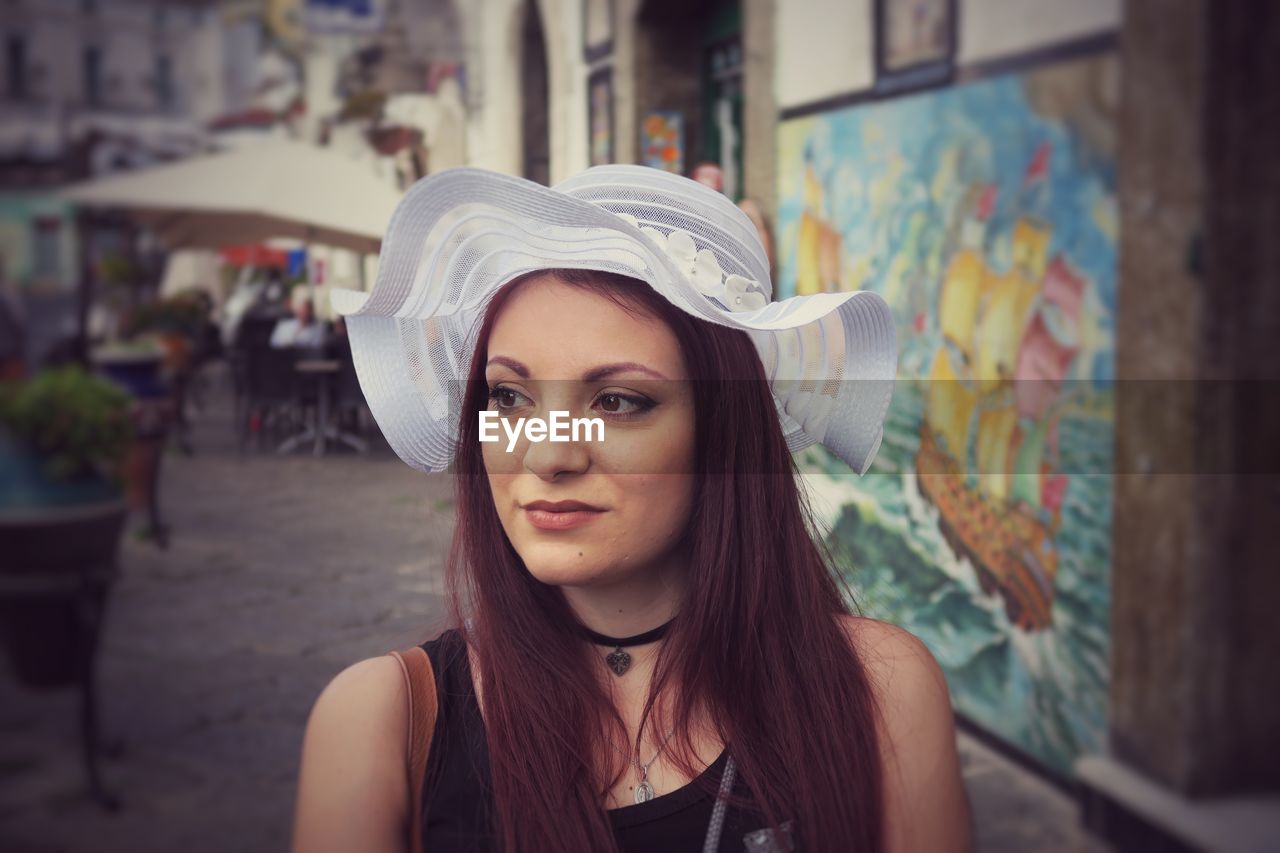 Thoughtful young woman wearing hat on footpath