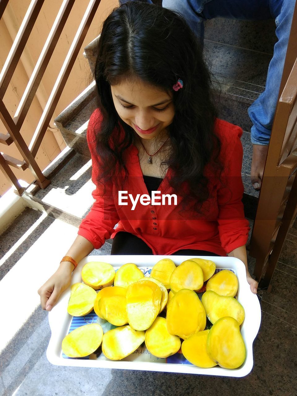 HIGH ANGLE VIEW OF YOUNG WOMAN HOLDING FOOD ON TABLE