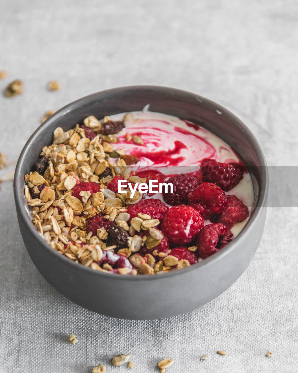 High angle view of breakfast yoghurt with raspberries and granola served in bowl