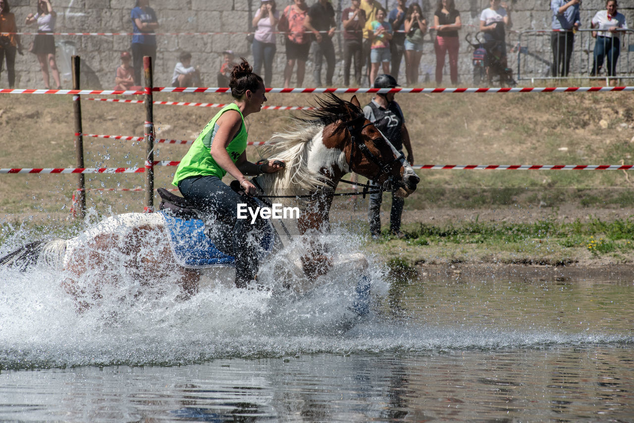 PEOPLE RIDING HORSE IN WATER