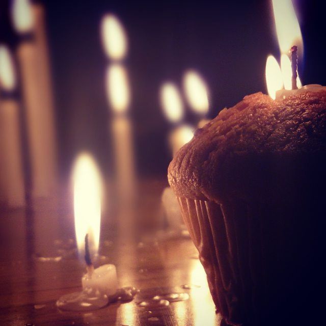 CLOSE-UP OF LIT CANDLE IN DARK ROOM