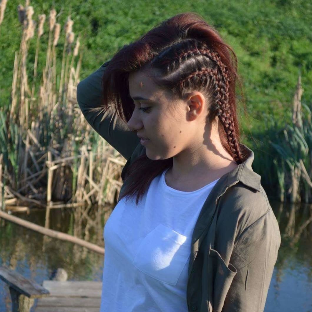 Woman with braided hair looking down outdoors